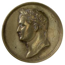 Round medal with male profile facing left.