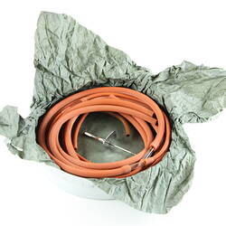 Orange rubber tubing and metal cannula on green paper tissue.