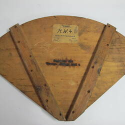 Quadrant of wood with label and heat branded text, underside view.
