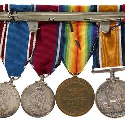 Reverse of a group of six metal medals suspended from multi coloured ribbons.