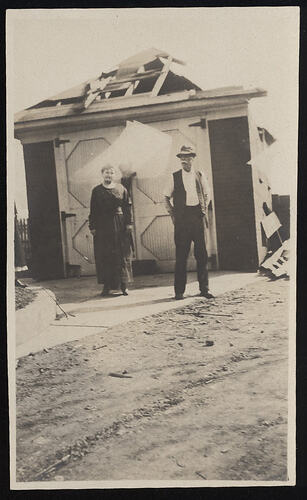 Monochrome photograph of a pair near a garage.