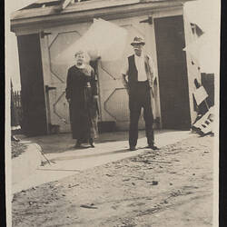 Monochrome photograph of a pair near a garage.