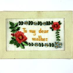 Front of postcard with embroidered flowers and words.