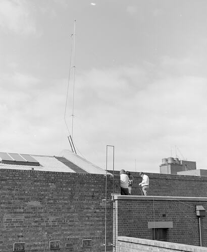 Workers installing radio broadcasting antenna on roof of Science Museum, Melbourne, 23 February 1974