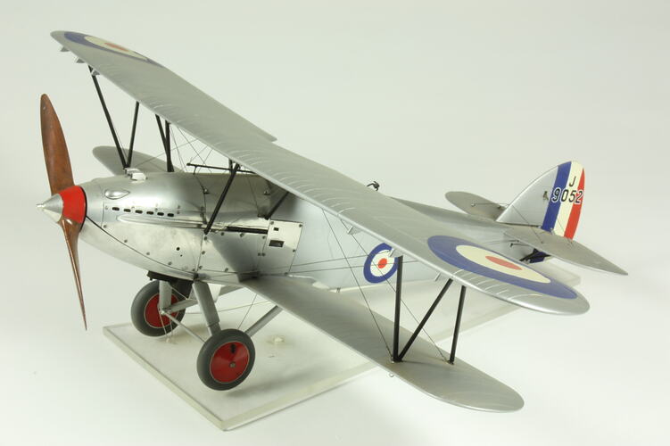 Silver model aeroplane with single front propellor, red and black wheels.