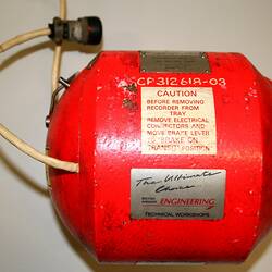Bright orange-red metal cylindrical casing with domed ends, plates and labels. Two cords fixed at ends.