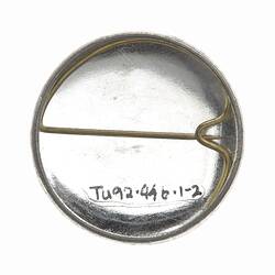Metal back of round badge. Horizontal pin.