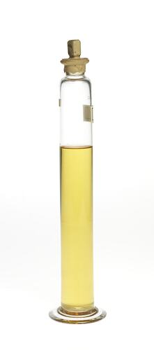 Cylindrical glass jar with yellow liquid. Two labels affixed, sealed at top.