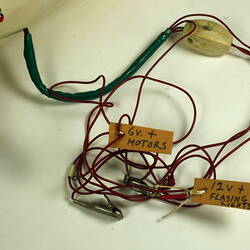 Detail of multi-coloured cables attached to white model body. Two tags on cables.