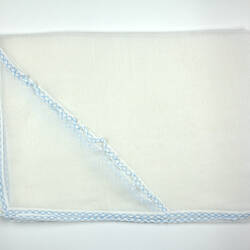 Folded piece of sheer white fabric with blue trim.