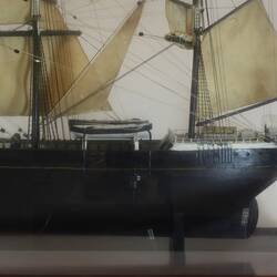 Detail of sailing ship model in glass case, facing left.