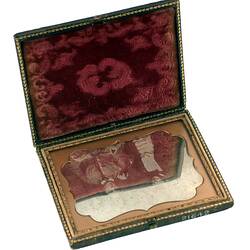 Open photo frame. Lined with red decorative velvet on top side and part portrait of man and woman on other.