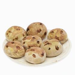 Model of seven miniature round buns with brown spots on a white plate.
