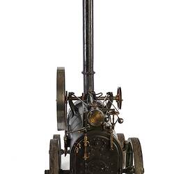 Model of black moveable steam engine on four wheels with tall chimney at front. Back view.