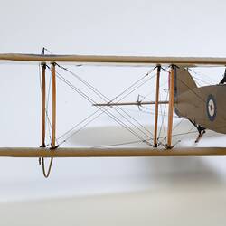 Model biplane aeroplane painted mustard brown. Front view of right wing.