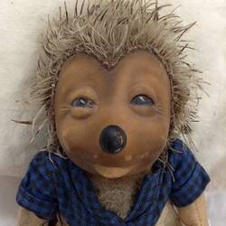 Hedgehog doll wearing blue and black chequered top.