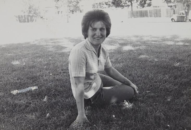 Woman smiling sitting on grass.