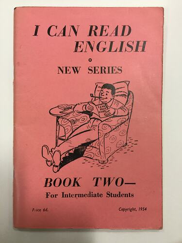 Red covered book with black cartoon of man sitting on sofa chair reading. Text above and below.