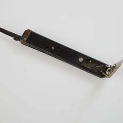 Quill pen cutter with black handle. Engraved silver metal quill cutter open at one end, open knife at other.