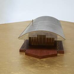 Model of a house with an arched roof, corrugated iron and wide expanses of glass.