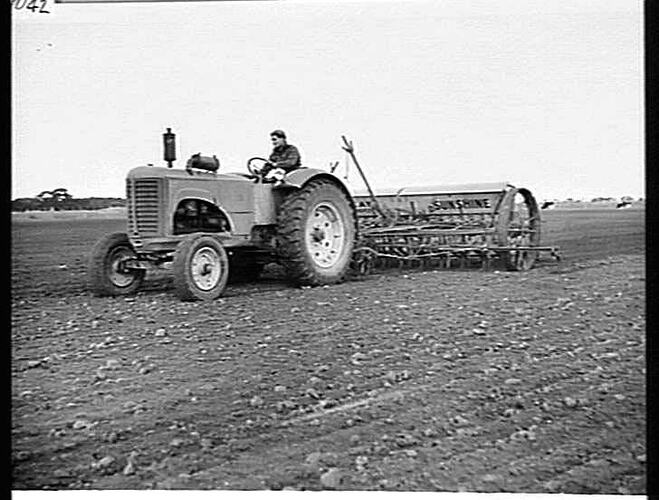 MR. MARTIN HAND, JEPARIT, VIC, WITH HIS 20-ROW `SUNTYNE', DRAWN BY A SUNSHINE MASSEY HARRIS TRACTOR AND WITH `SUNTOW' STUMP JUMP SMOOTHING HARROWS BEHIND, SOWING OATS AND FERTILIZER: JUNE 1949