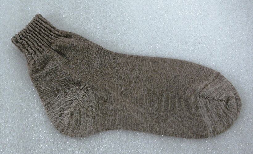 Side view of brown sock, lying flat.