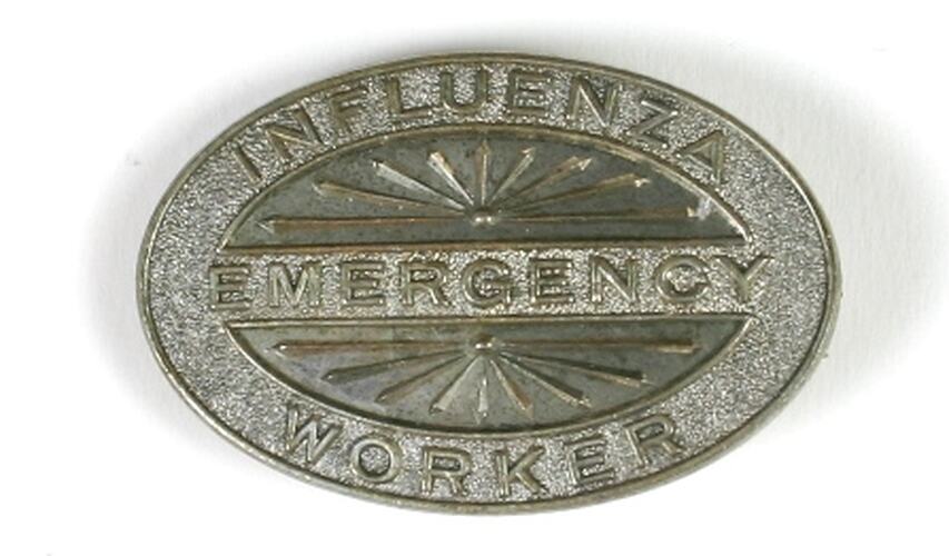 Elliptical metal badge with stamped text.
