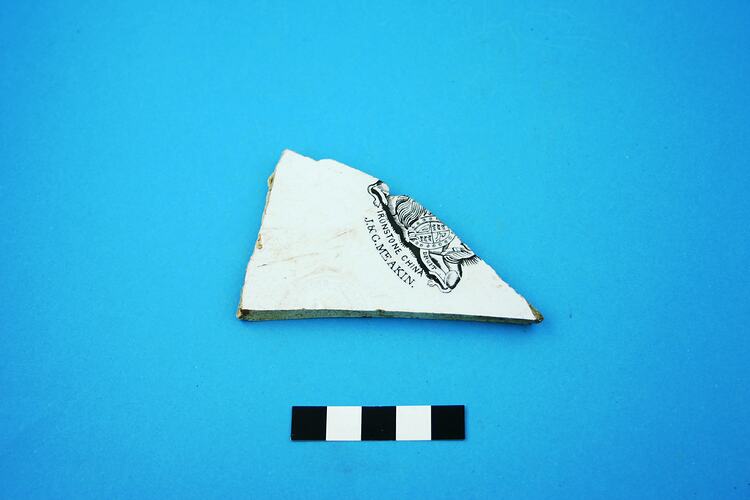 Triangular fragment from a white glazed ceramic plate.