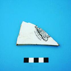 Triangular fragment from a white glazed ceramic plate.