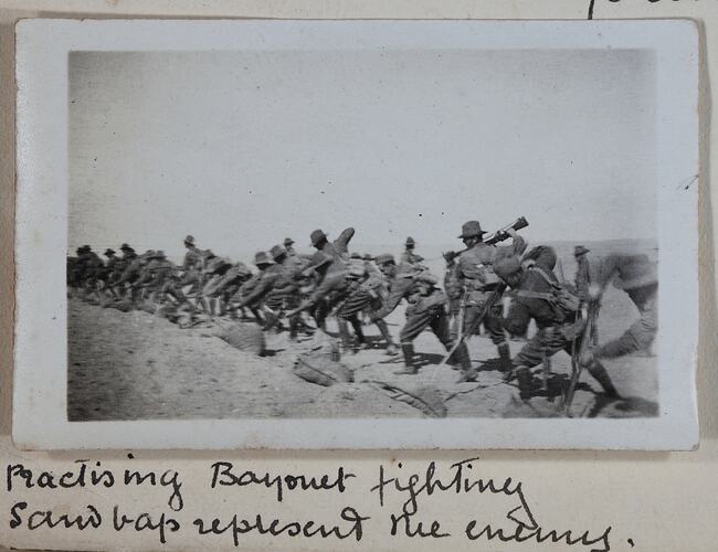 Row of servicemen stabbing sandbags with bayonets.