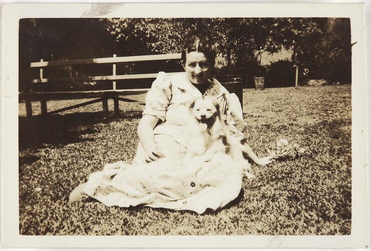 Mrs Gladys Clarke with Skipper, a Pomeranian crossbreed dog, on her lap, in the garden area of the Kodak Australasia Pty Ltd factory site in Abbotsford, in the early 1940s.