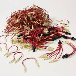 Pile of red electrical wires with small metal pins at the ends.