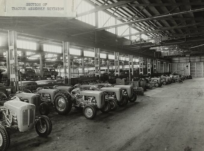 Row of tractors and motor cars in a factory.