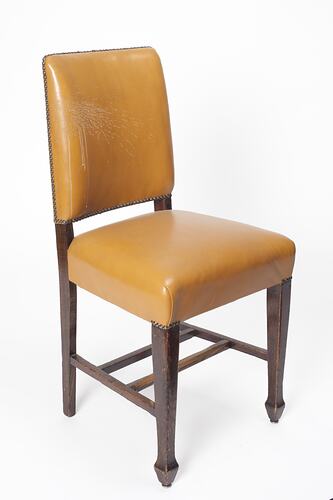 Yellow furnished chair with dark wood legs.