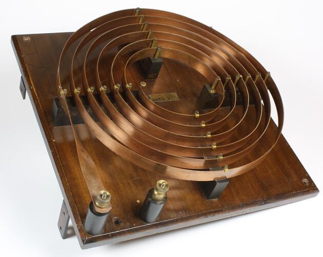 Copper coil mounted on a wooden board.
