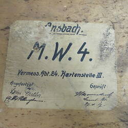 Label stuck to wood, with blue written text.