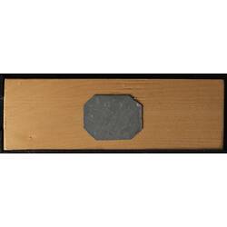 Underside of wooden microslide with octagonal metal central panel.