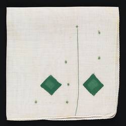 Folded handkerchief with green embroidered diamonds.