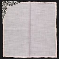 Unfolded pink handkerchief with lace corner.
