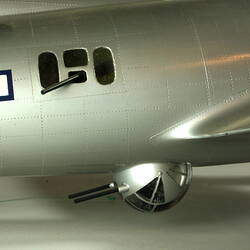 Silver model aeroplane. Detail of side with gunner section below.