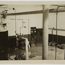 Generators under water. At left are large pipes and a light bulb hanging from the ceiling.