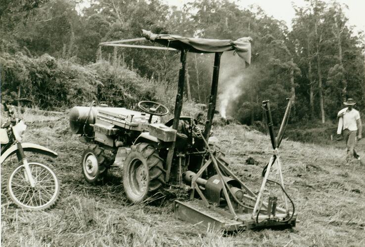 Tractor and rotary slasher in field.