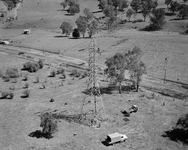 Aerial view of power pylon and its stringing cable in pastoral setting.