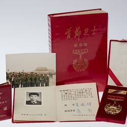Group of items. Gold medal and bar in red velvet case, book with photos, two smaller books and loose photo.