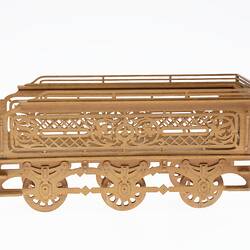 Wooden tender model made of fretwork. Has three pairs of moving wheels. Left profile.