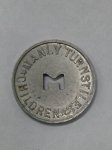 Round coin with M cut out of centre.