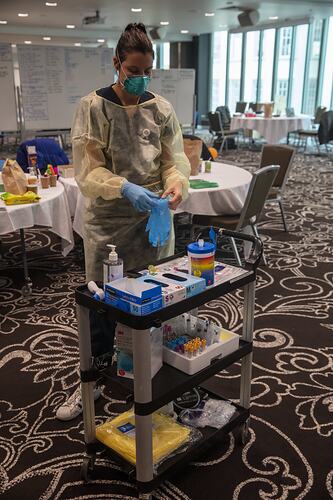 Woman putting on PPE, Novotel, Melbourne, 14 May 2020