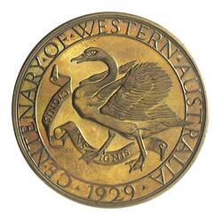 Round gold-coloured medal with swan advancing left with wings spread, text around edge.