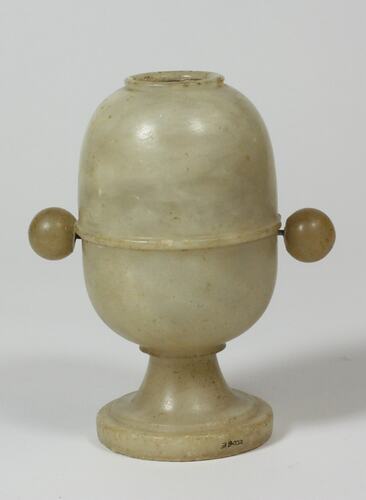 Alabaster egg with stand, in one piece. Round viewing lens on top. Ball shaped turning knobs on each side.