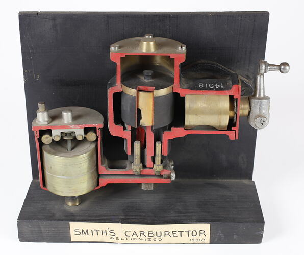 Sectioned Smith's carburettor on black stand with label.